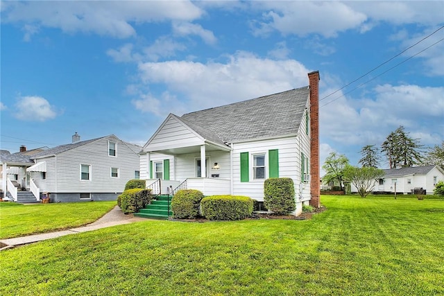 view of front of property featuring a chimney, a front yard, covered porch, and roof with shingles