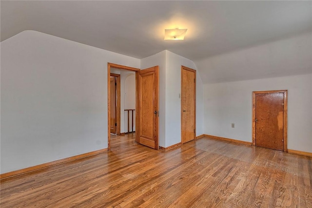 additional living space featuring vaulted ceiling, light wood finished floors, and baseboards