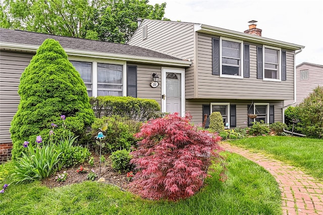 split level home with a chimney and a front lawn