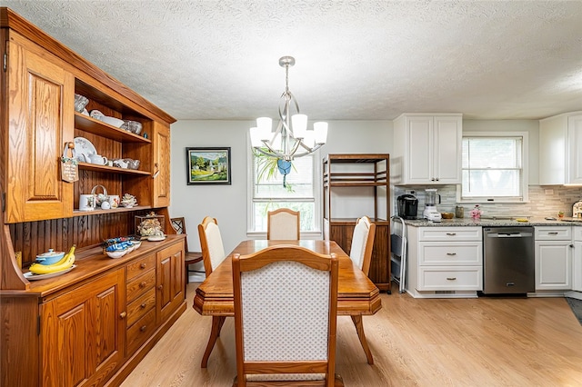 dining space with light wood-style flooring, a chandelier, and a textured ceiling
