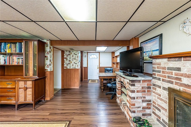 office with a drop ceiling, wood finished floors, wainscoting, and a fireplace