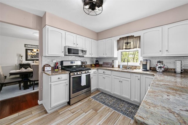 9204 Douglas Fir Dr, Plum Boro, PA 15239 - kitchen with stainless steel appliances, a sink, backsplash, white cabinetry, and light wood-style floors
