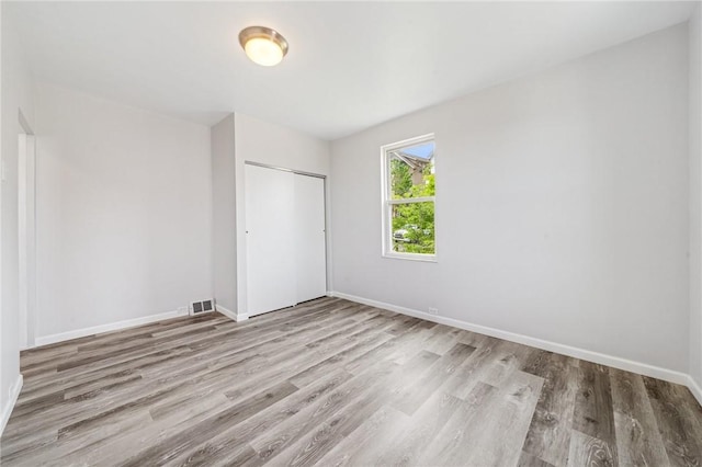 unfurnished bedroom with wood finished floors, a closet, and baseboards