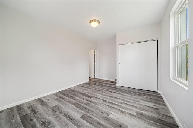 unfurnished bedroom with wood finished floors, a closet, and baseboards