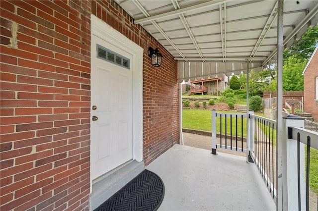 doorway to property featuring covered porch and brick siding