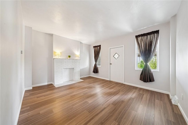 unfurnished living room featuring wood finished floors, baseboards, and a fireplace