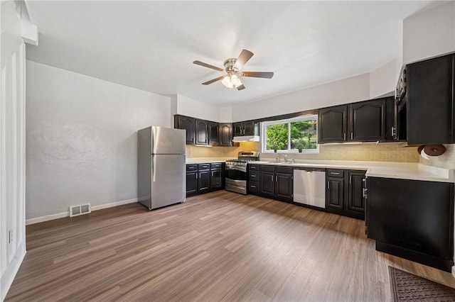 kitchen with stainless steel appliances, a ceiling fan, tasteful backsplash, light countertops, and light wood finished floors
