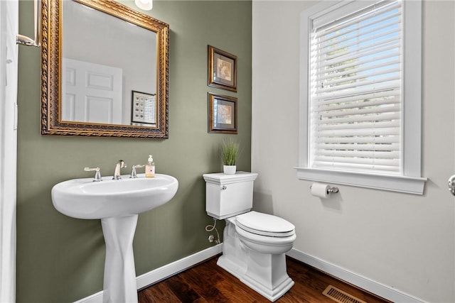 bathroom with baseboards, toilet, wood finished floors, and a sink
