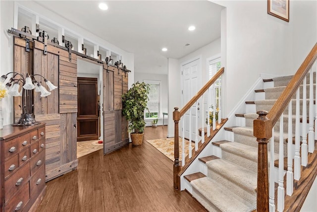 foyer entrance featuring a barn door, dark wood-style floors, stairs, and recessed lighting