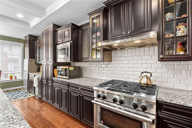 kitchen featuring stainless steel appliances, under cabinet range hood, light wood-style flooring, beverage cooler, and backsplash