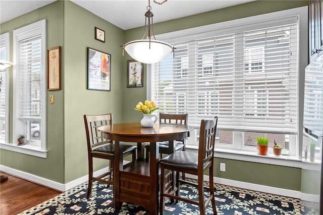 dining space with baseboards, plenty of natural light, and wood finished floors