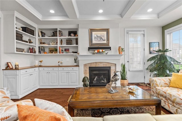 living area with wood finished floors, coffered ceiling, beam ceiling, a tiled fireplace, and recessed lighting