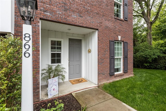 property entrance featuring brick siding and a lawn