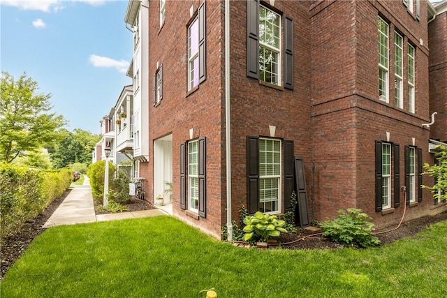view of side of property featuring brick siding and a yard