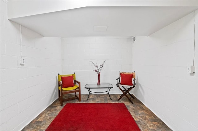 living area with concrete block wall and dark stone finish flooring