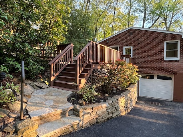 view of front of property with stairs, a wooden deck, brick siding, and driveway
