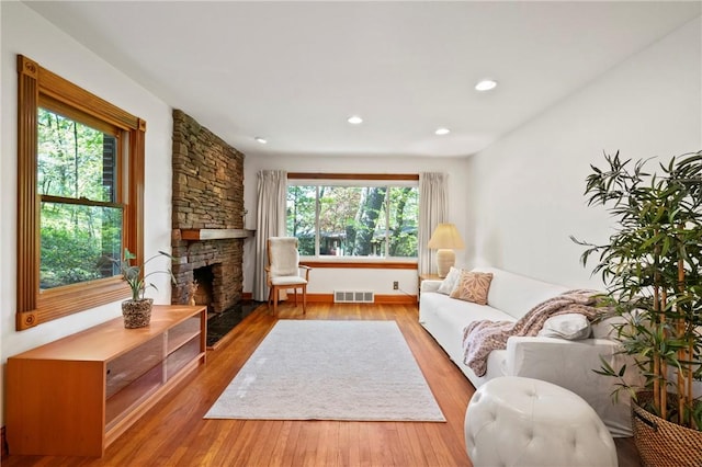 living area with a fireplace, wood finished floors, recessed lighting, and baseboards