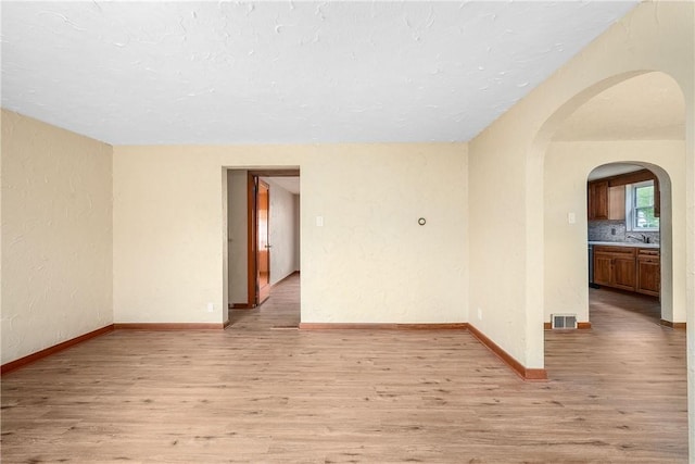 533 Freeport Rd, New Kensington, PA 15068 - unfurnished room featuring light wood-type flooring, arched walkways, a sink, baseboards, and a textured wall