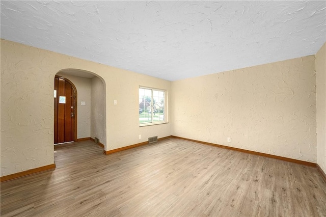 533 Freeport Rd, New Kensington, PA 15068 - spare room with arched walkways, a textured wall, a textured ceiling, light wood-type flooring, and baseboards