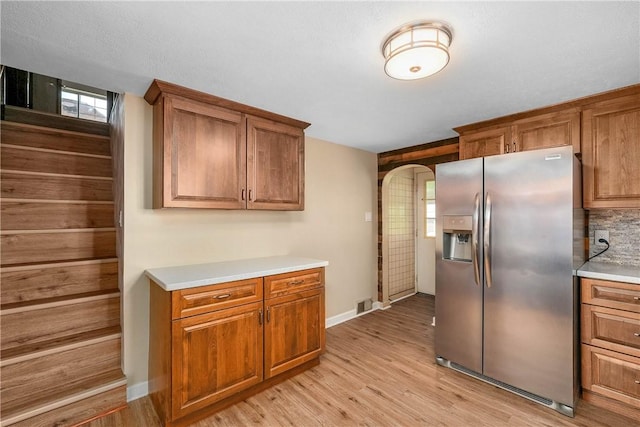 533 Freeport Rd, New Kensington, PA 15068 - kitchen with stainless steel refrigerator with ice dispenser, brown cabinetry, light wood-style floors, arched walkways, and light countertops