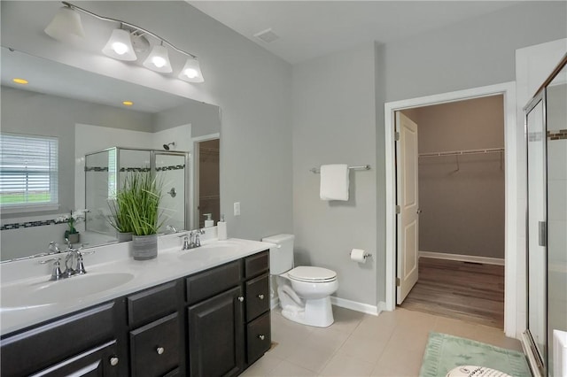 full bath featuring tile patterned flooring, a stall shower, a walk in closet, and double vanity