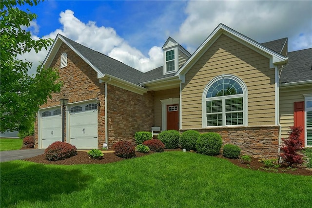 view of front of house with stone siding, a garage, a front lawn, and a shingled roof
