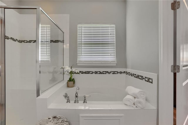 full bathroom with a shower stall and a bath