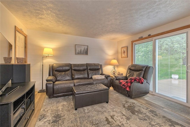 living area featuring wood finished floors, a textured ceiling, and wood walls