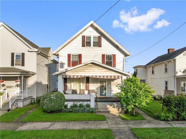 american foursquare style home featuring covered porch and a front yard