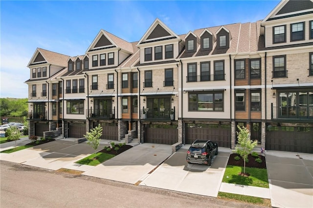 multi unit property featuring an attached garage, driveway, and a residential view