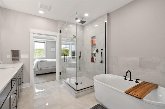 ensuite bathroom featuring marble tiled flooring, a stall shower, a freestanding bath, vanity, and recessed lighting