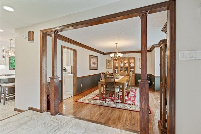 304 Diana Dr, Robinson Twp Nwa, PA 15136 - dining space with a chandelier, a wainscoted wall, decorative columns, crown molding, and light wood-type flooring