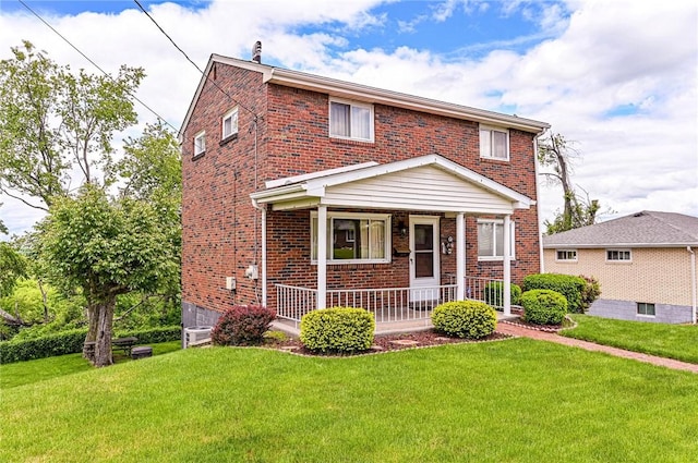 view of front of property with brick siding, a porch, and a front yard