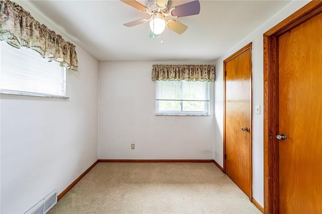 empty room with carpet flooring, a ceiling fan, and baseboards