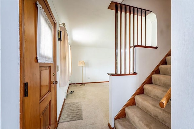 entrance foyer featuring light colored carpet, stairs, and baseboards