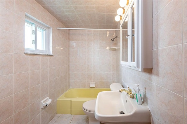full bath with tile walls, toilet, a sink, tub / shower combination, and tile patterned floors