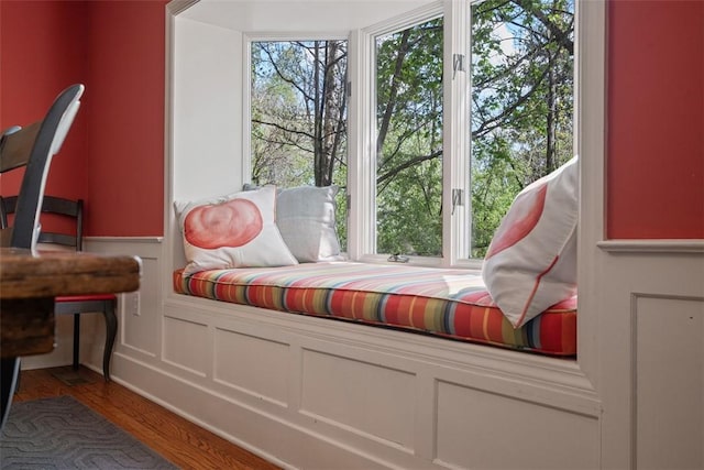 sitting room with wainscoting, wood finished floors, and a decorative wall