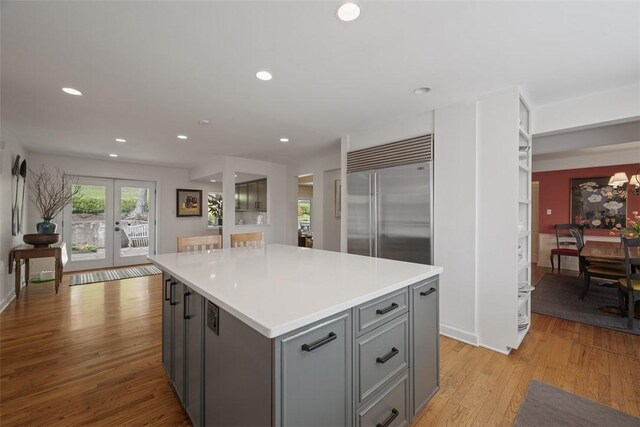 kitchen featuring gray cabinetry, built in fridge, light wood-type flooring, light countertops, and a kitchen island