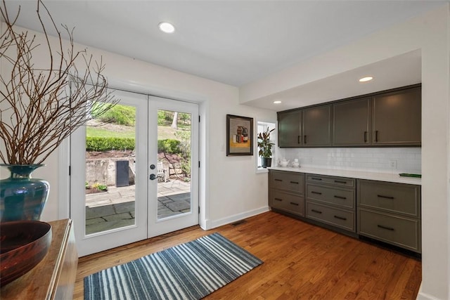 kitchen featuring french doors, tasteful backsplash, wood finished floors, light countertops, and recessed lighting