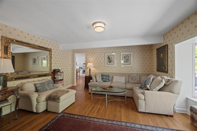 living area featuring wallpapered walls, wood finished floors, and baseboards