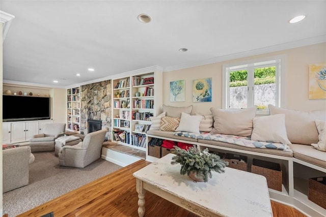 living room featuring crown molding, wood finished floors, a stone fireplace, built in features, and recessed lighting