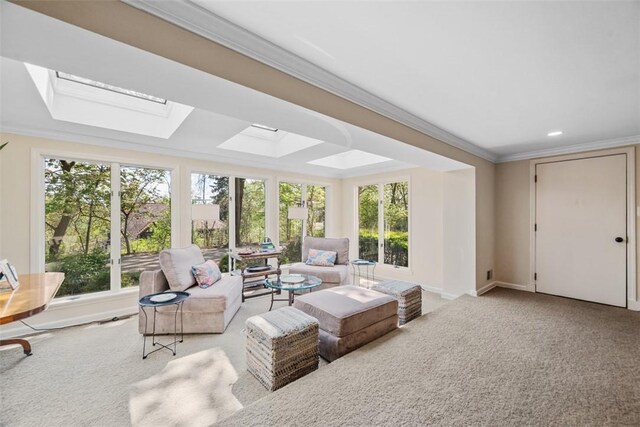 living room featuring healthy amount of natural light, crown molding, carpet floors, a skylight, and baseboards
