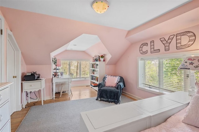bedroom with light wood finished floors, vaulted ceiling, a desk, and baseboards