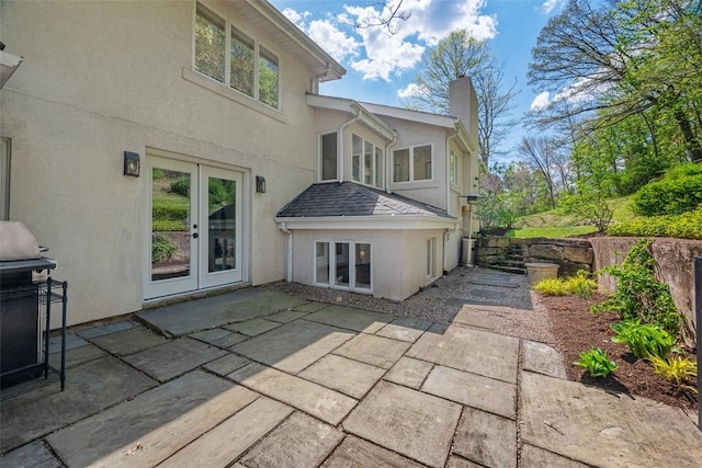 back of property featuring a chimney, french doors, a patio, and stucco siding