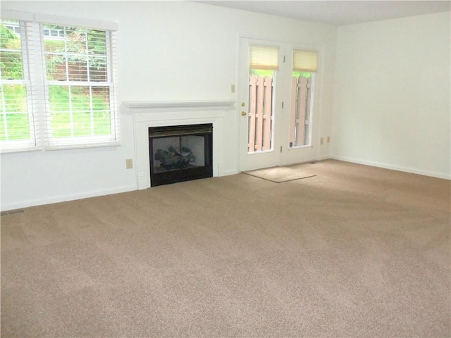 unfurnished living room with carpet floors, a fireplace, and baseboards