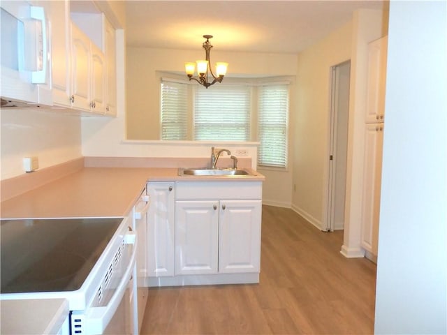 kitchen with a sink, white appliances, a chandelier, white cabinetry, and light wood-style floors