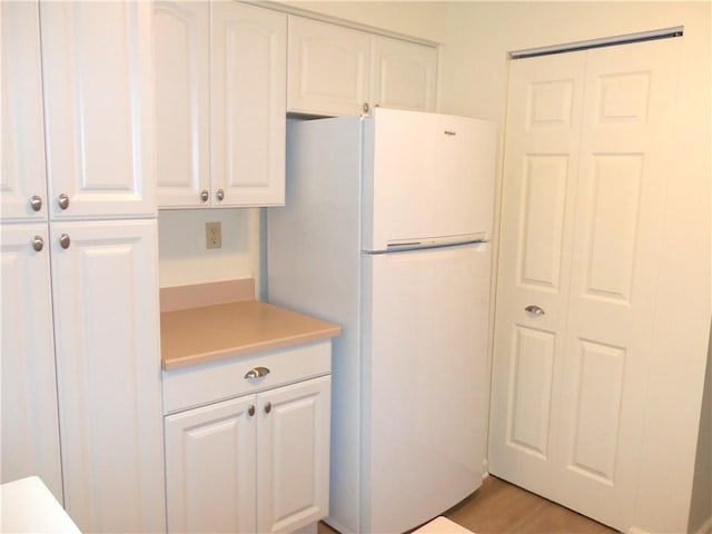 kitchen featuring freestanding refrigerator, white cabinetry, and light countertops