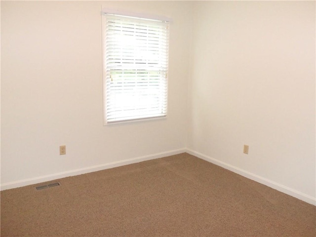 spare room featuring carpet flooring and baseboards