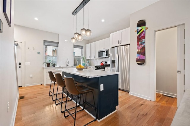 kitchen with stainless steel appliances, light wood-style flooring, white cabinetry, a center island, and recessed lighting
