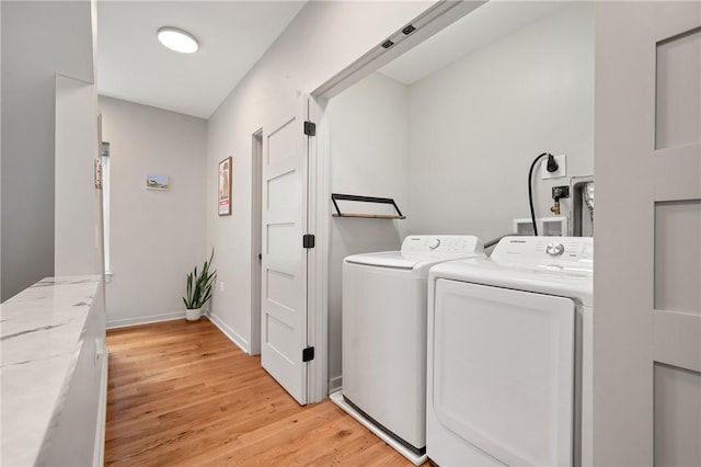 washroom featuring washing machine and clothes dryer, light wood-style flooring, and baseboards